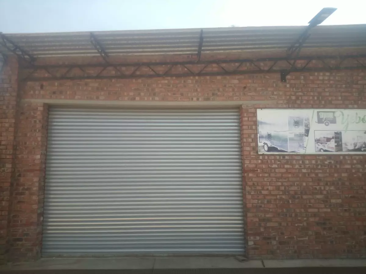 Brick workshop entrance with a large grey roller shutter door