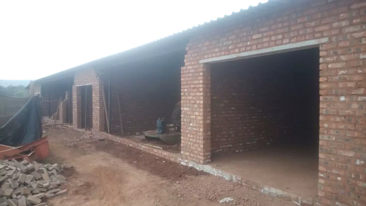 Long brick building under construction with large open doorways